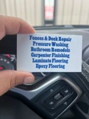 A hand holding a business card listing home improvement services, including fences, pressure washing, and flooring.