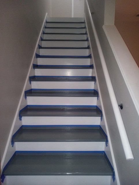 Gray and white painted staircase with a white railing on the right, gray walls to the left.