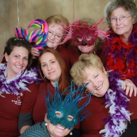 A group of women wearing masks and feathers posing for a picture