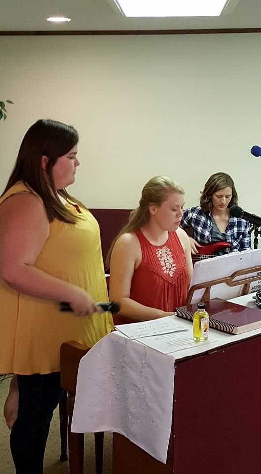 A group of women are standing around a podium singing into microphones.