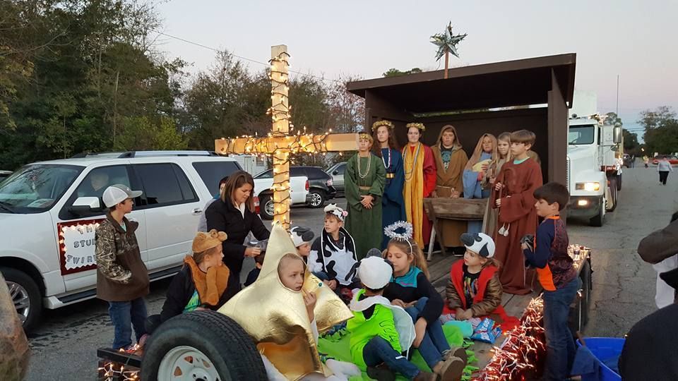 A group of people are standing around a float with a cross on it.