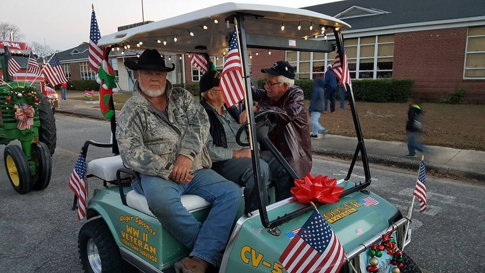 Three men are riding in a golf cart decorated with american flags.