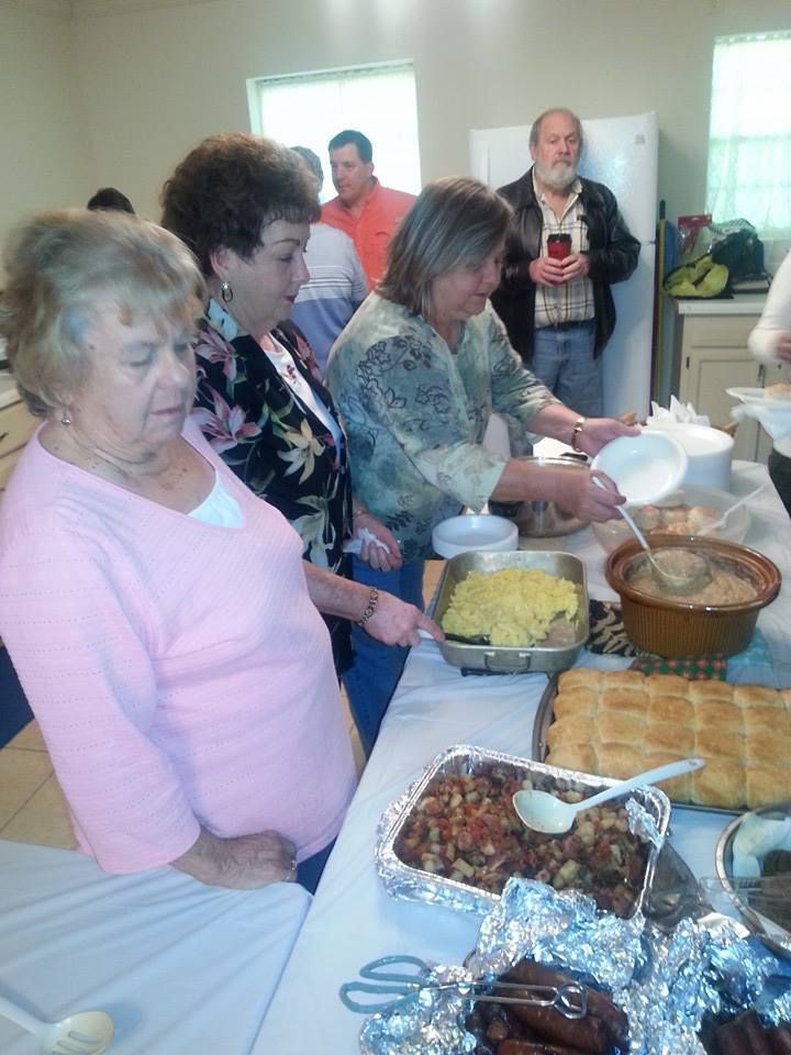 A group of people are standing around a table with food on it
