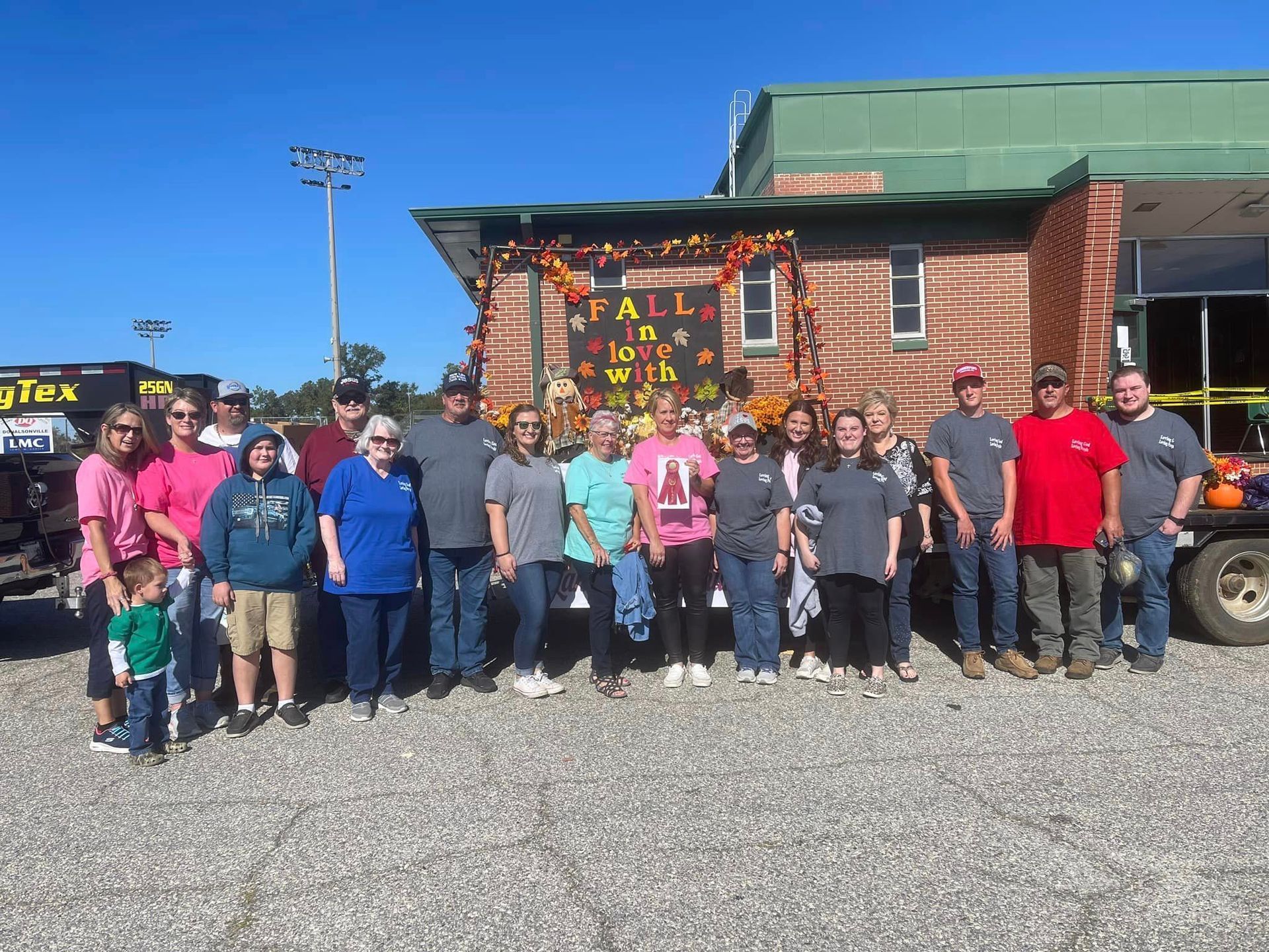 A group of people are posing for a picture in front of a building that says fall