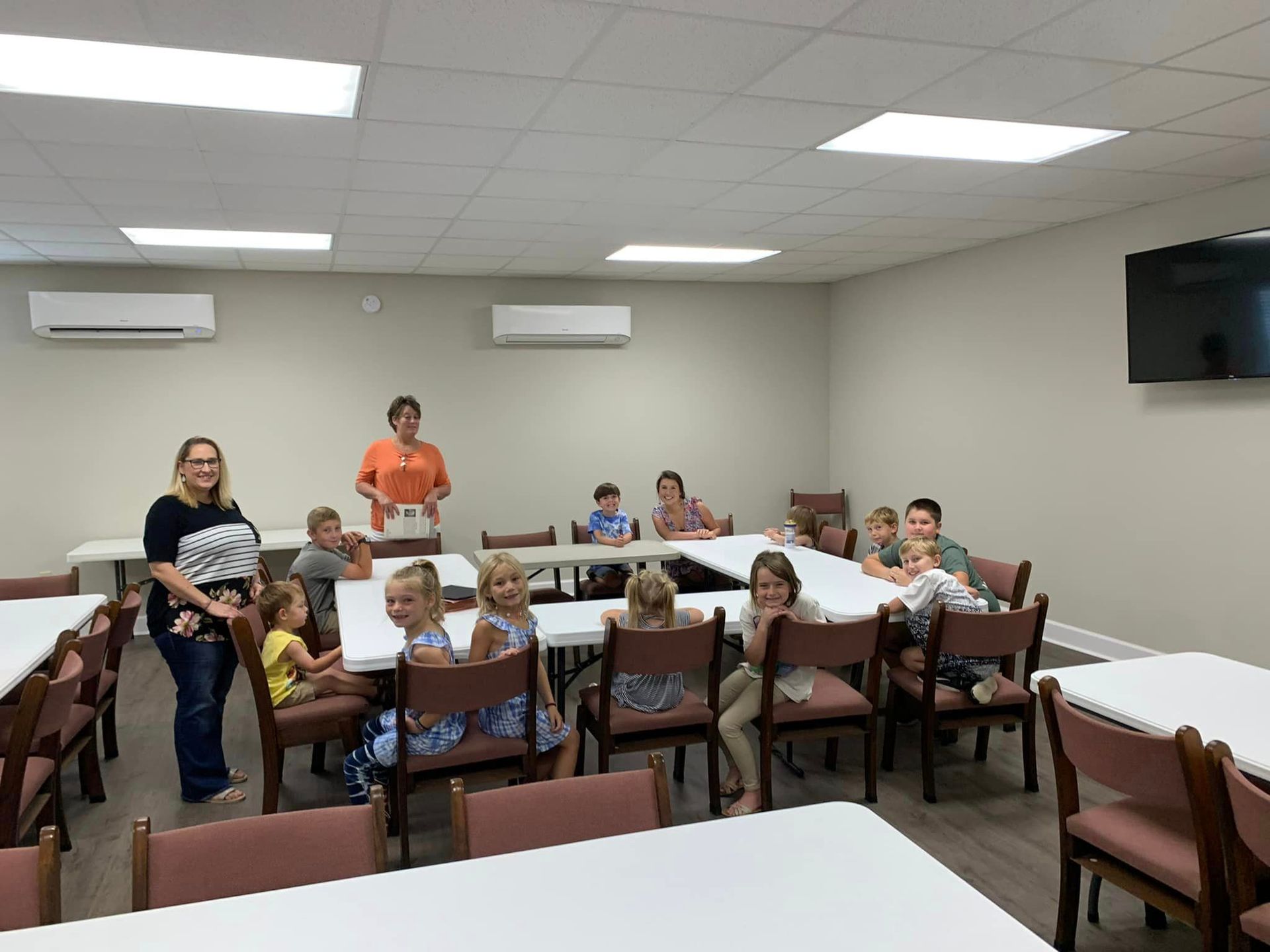 A group of children are sitting at tables in a room.