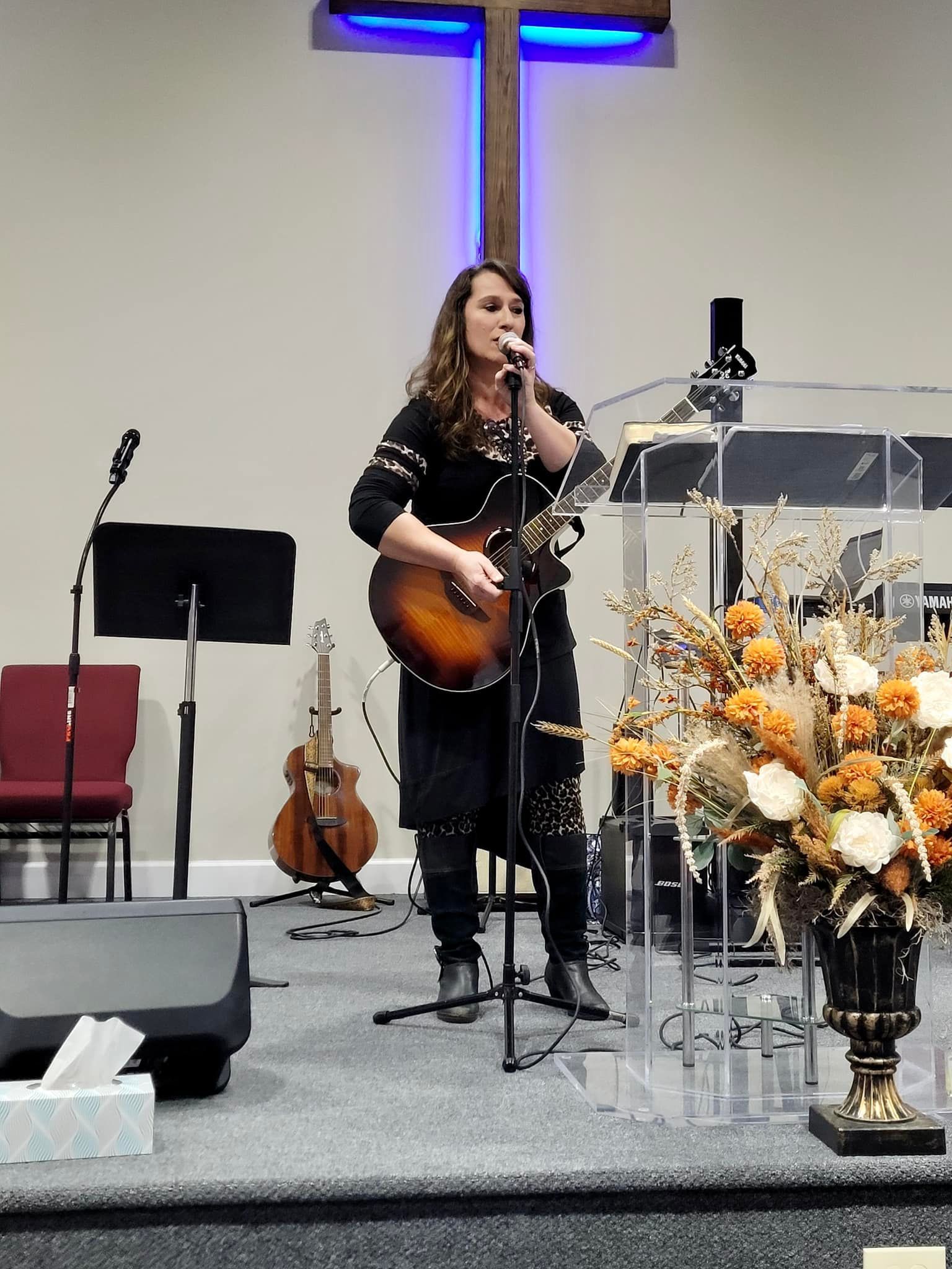 A woman singing into a microphone while holding a guitar