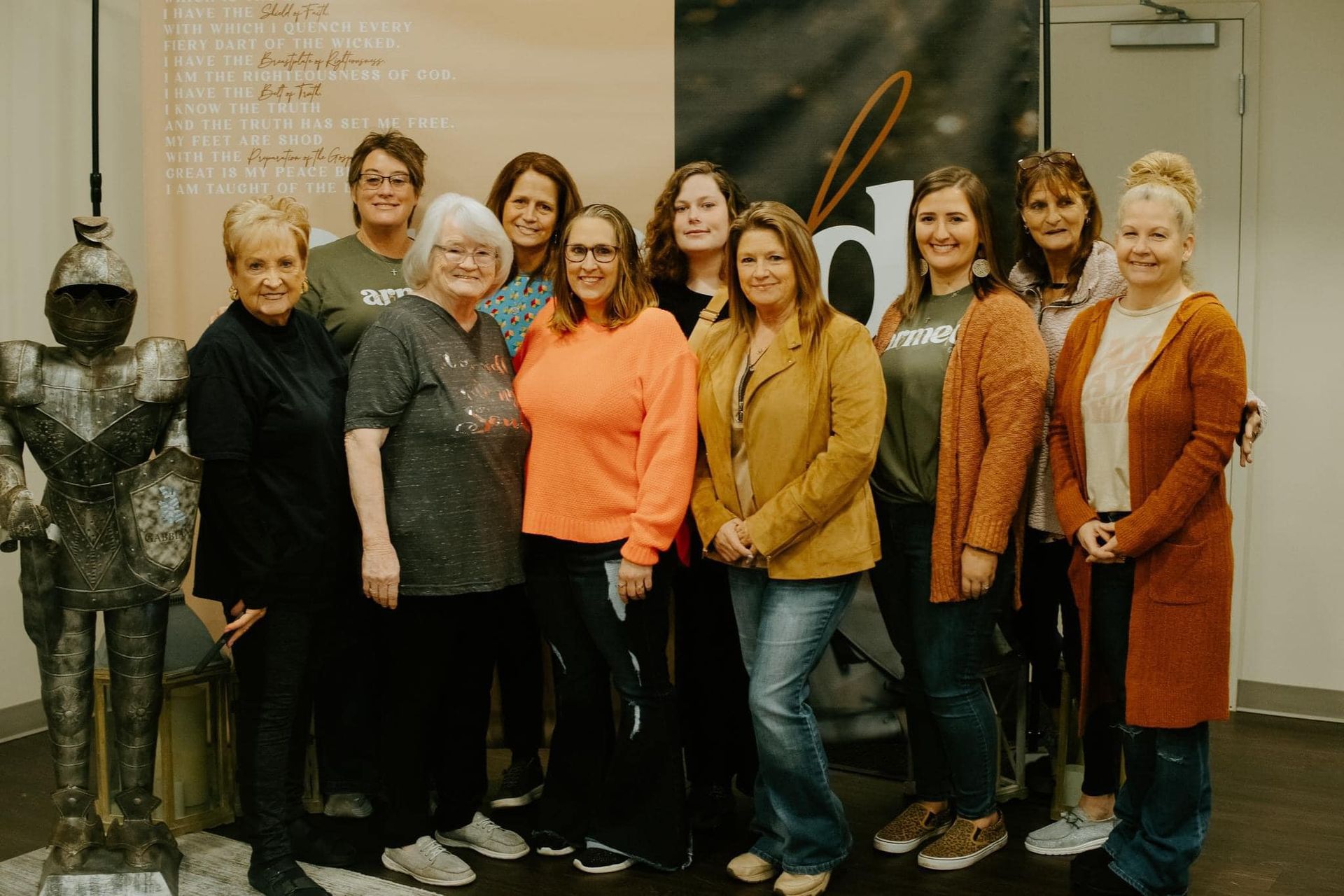 A group of women are posing for a picture in front of a statue of a knight.