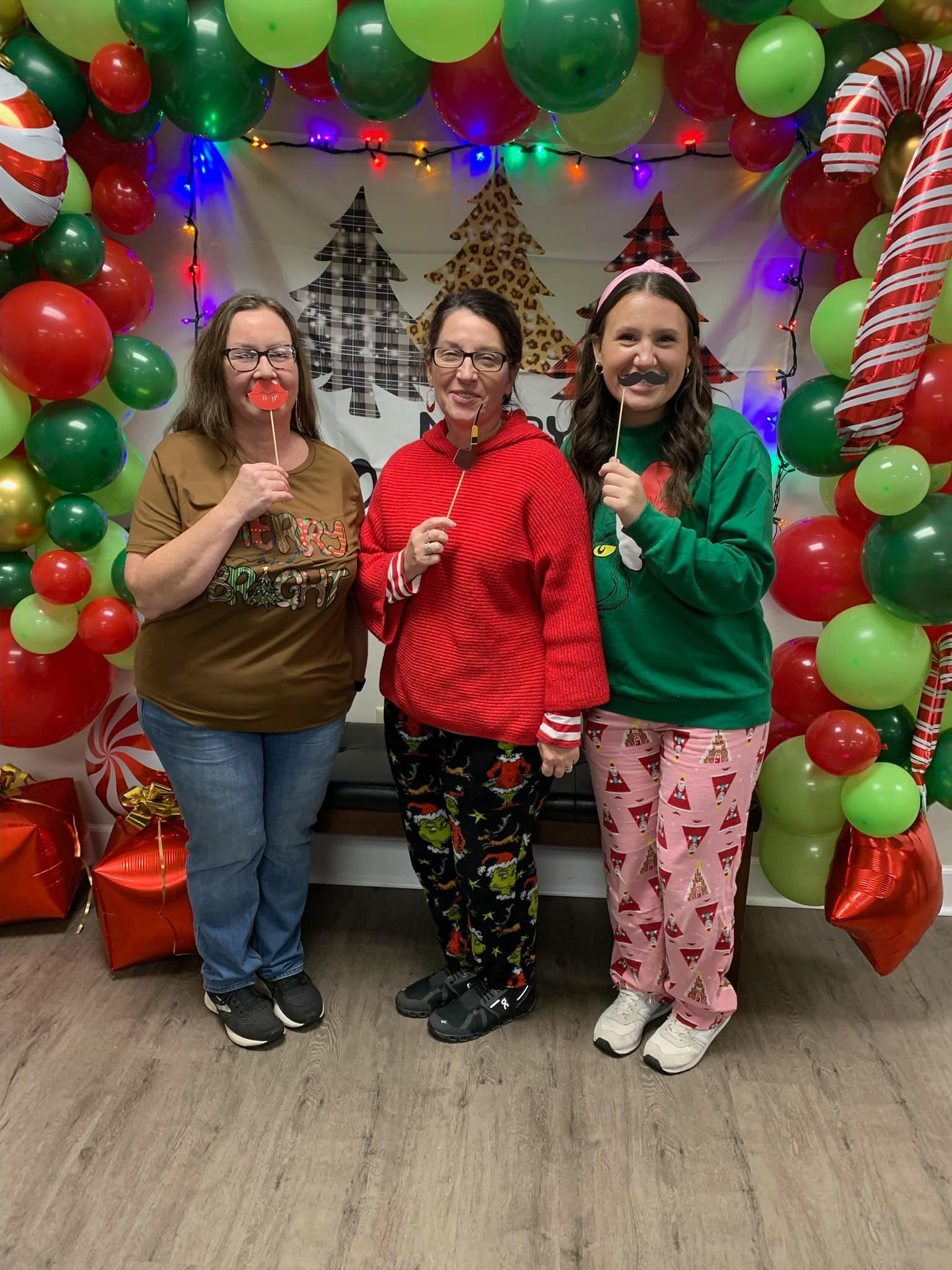 Three women are posing for a picture in front of a christmas decoration.