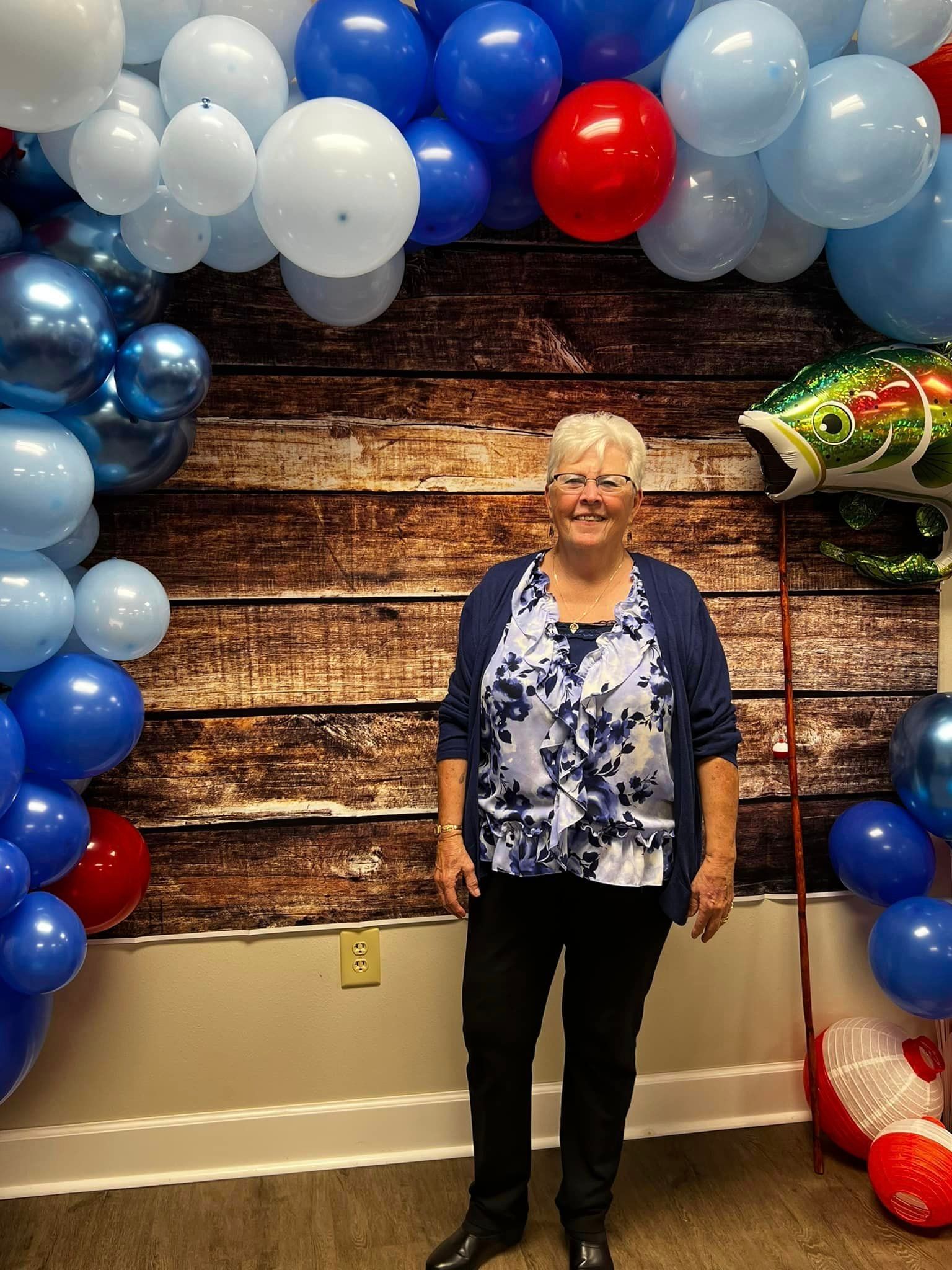 A woman is standing in front of a wall covered in balloons.