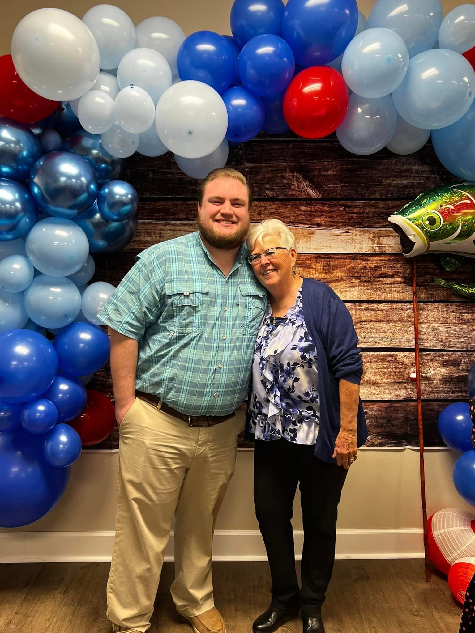A man and a woman are posing for a picture in front of balloons.