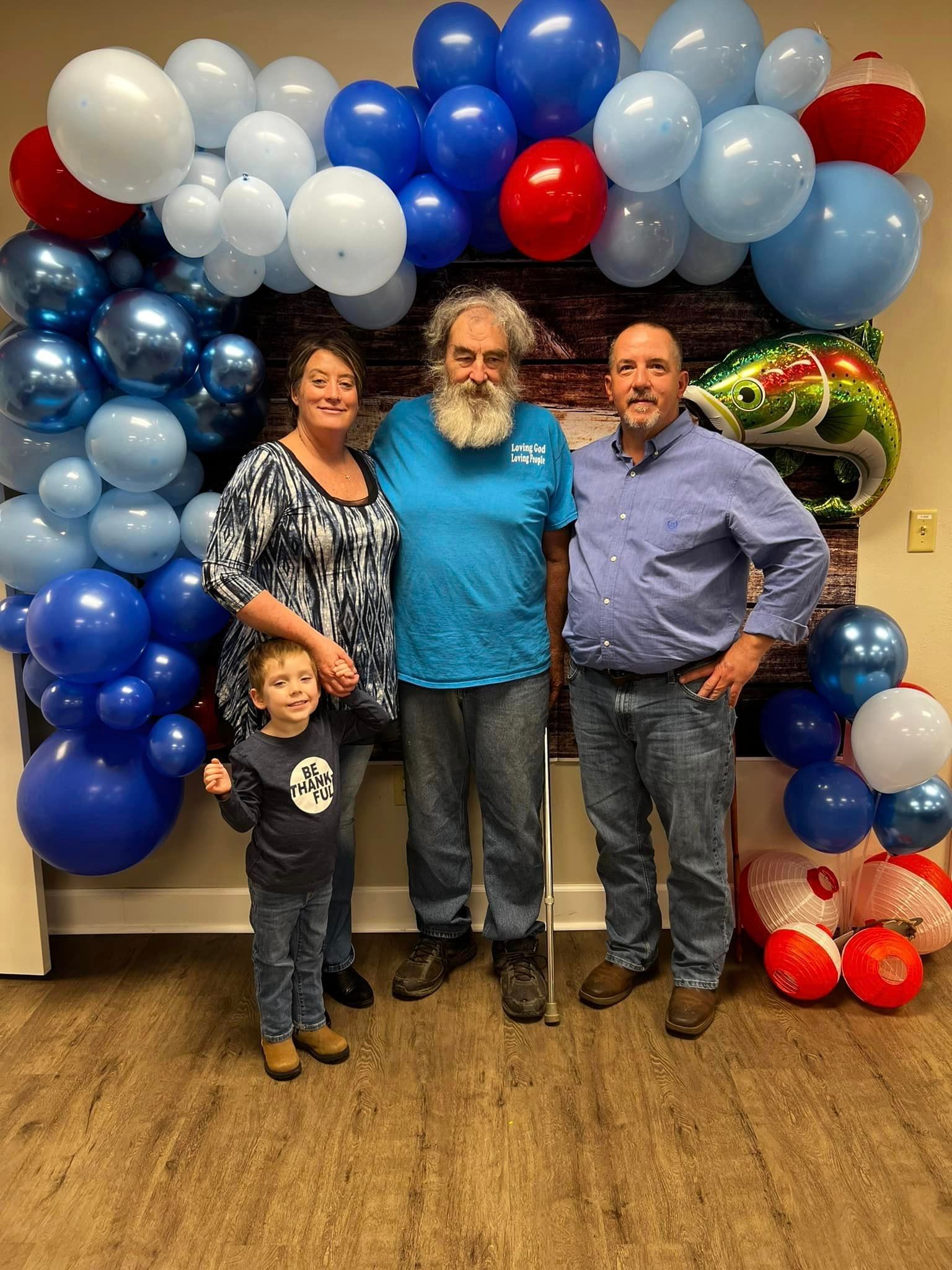 A family is posing for a picture in front of a wall of balloons.