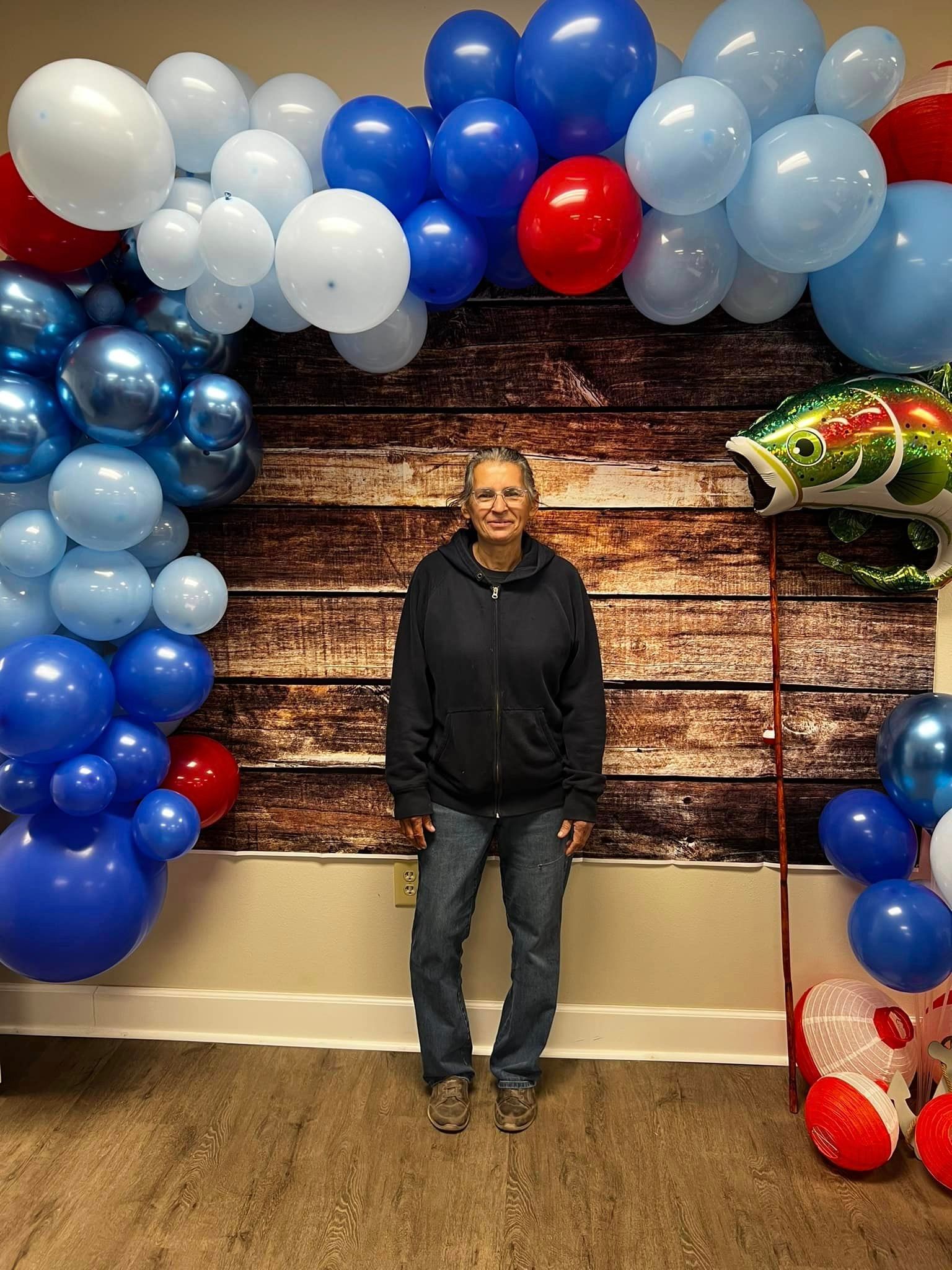A woman is standing in front of a wall covered in balloons.