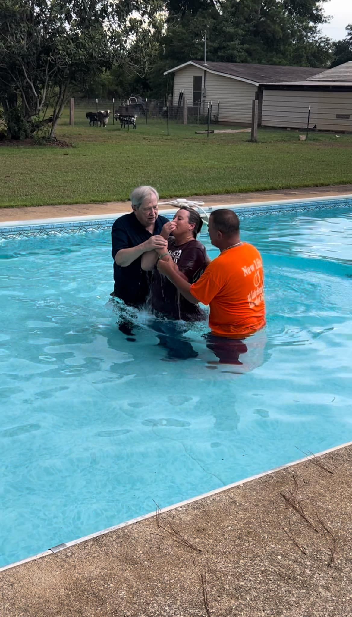 A man is being baptised in a swimming pool.