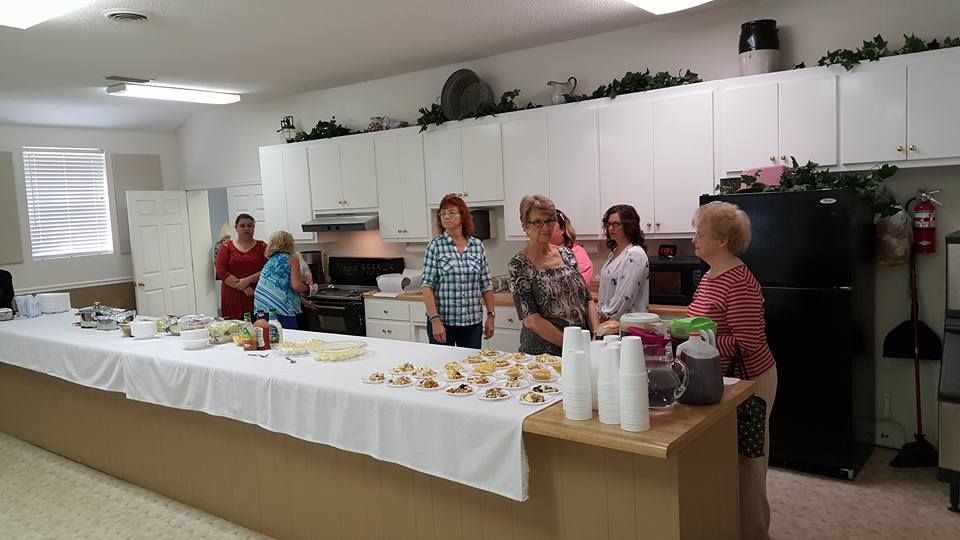 A group of women standing around a long table in a kitchen