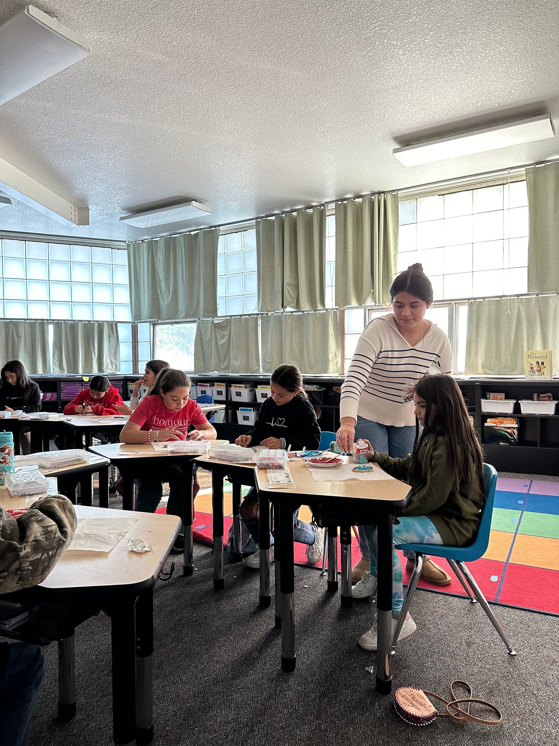 A group of children are sitting at tables in a classroom.