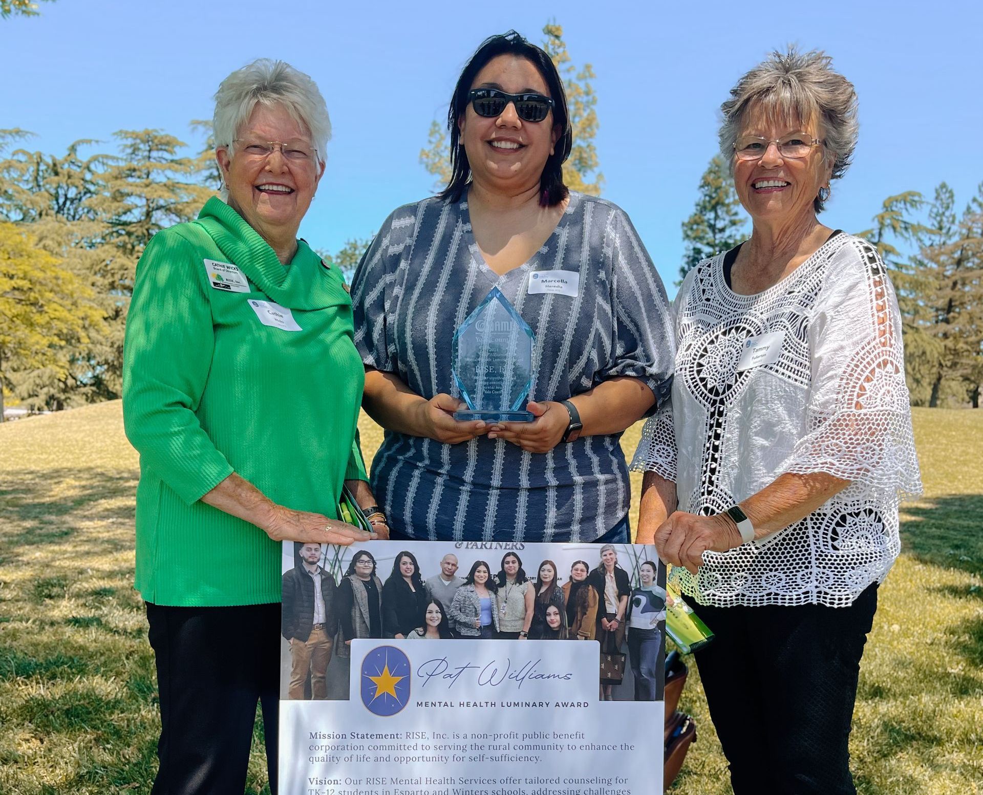 Three women standing next to each other holding a sign