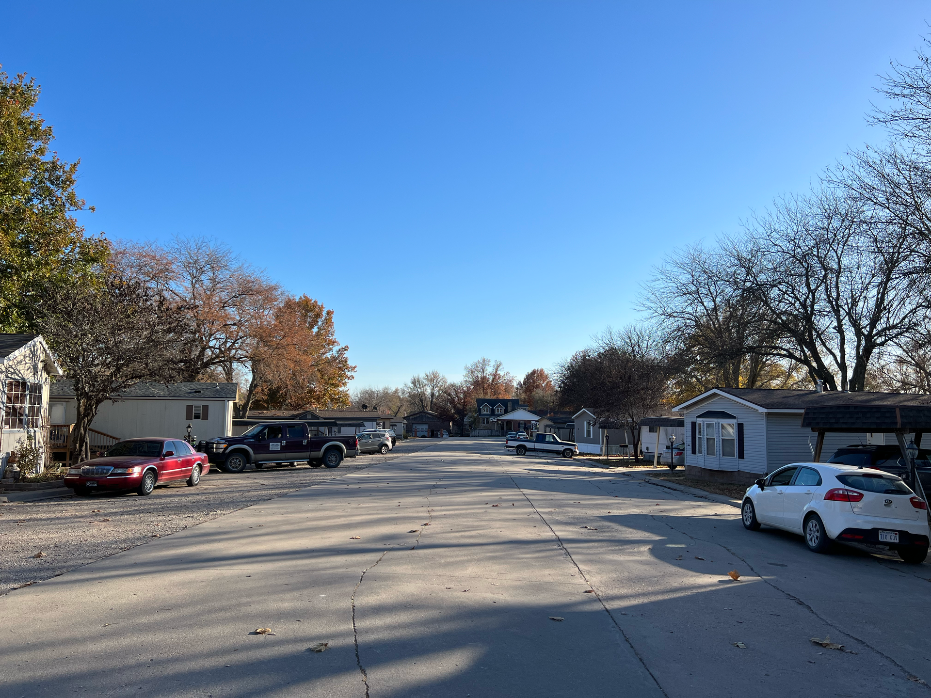 A white car is parked on the side of the road in a residential area.