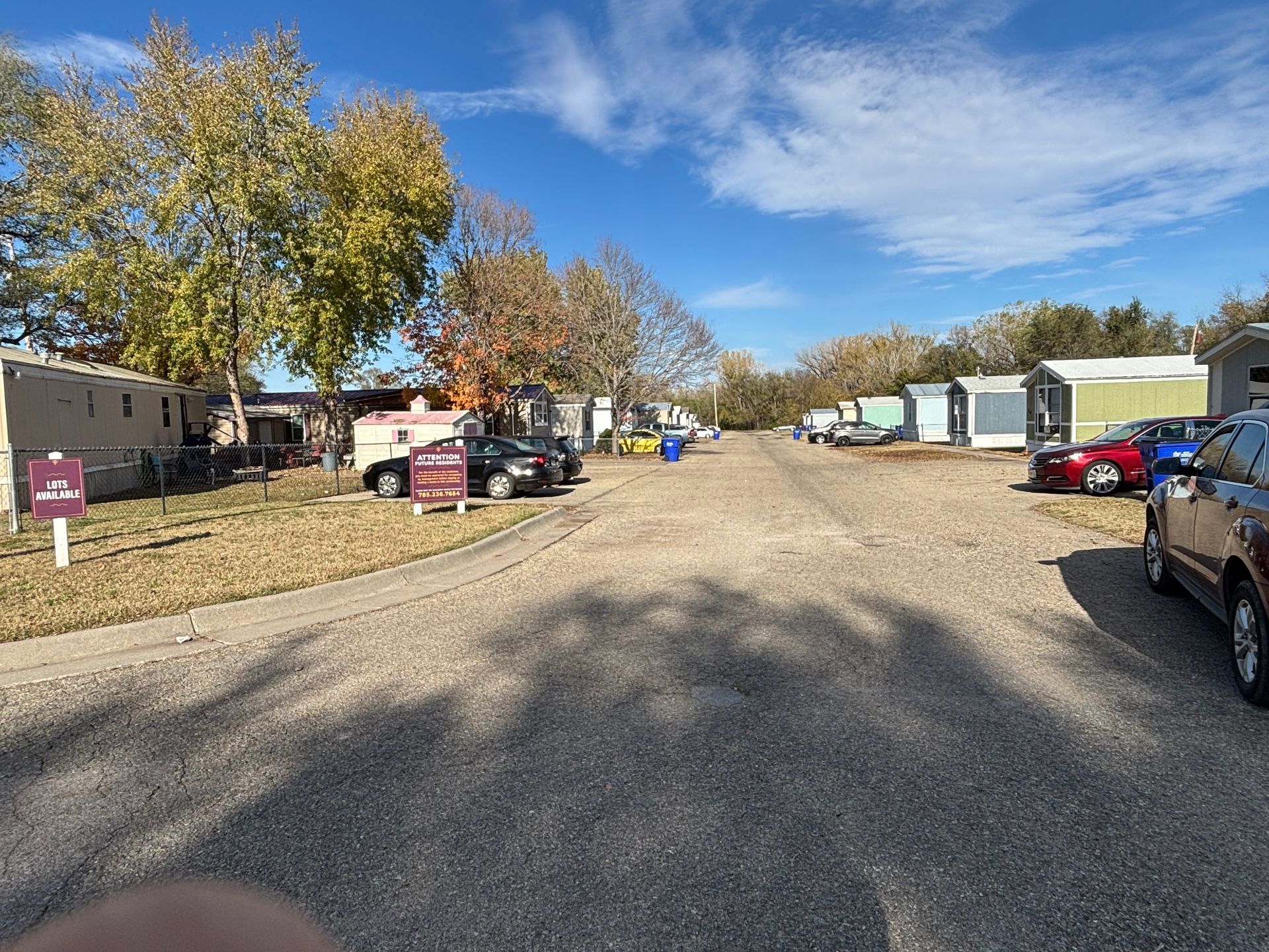 A lot of cars are parked on the side of the road in a mobile home park.