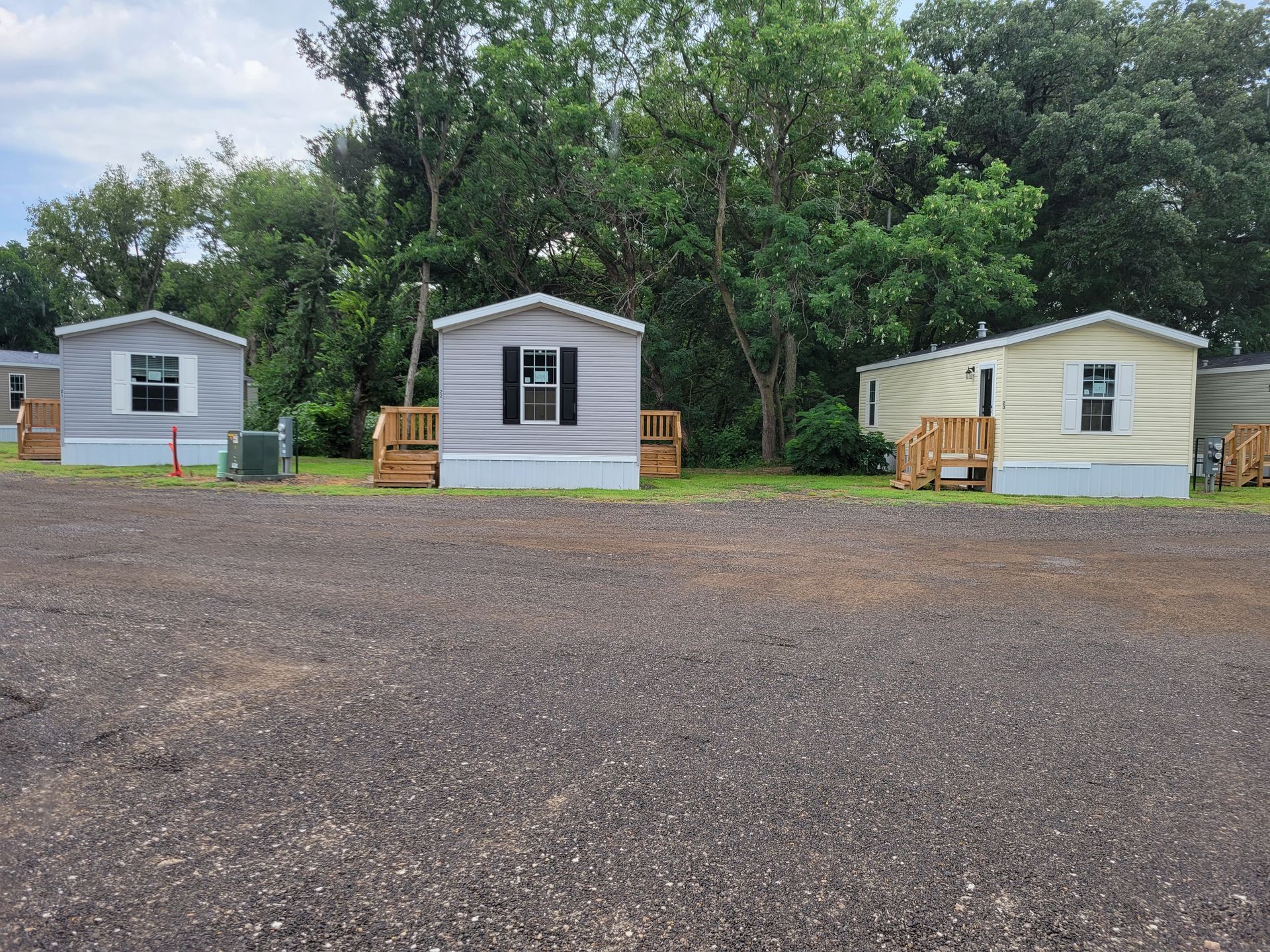 Three mobile homes are lined up in a parking lot.