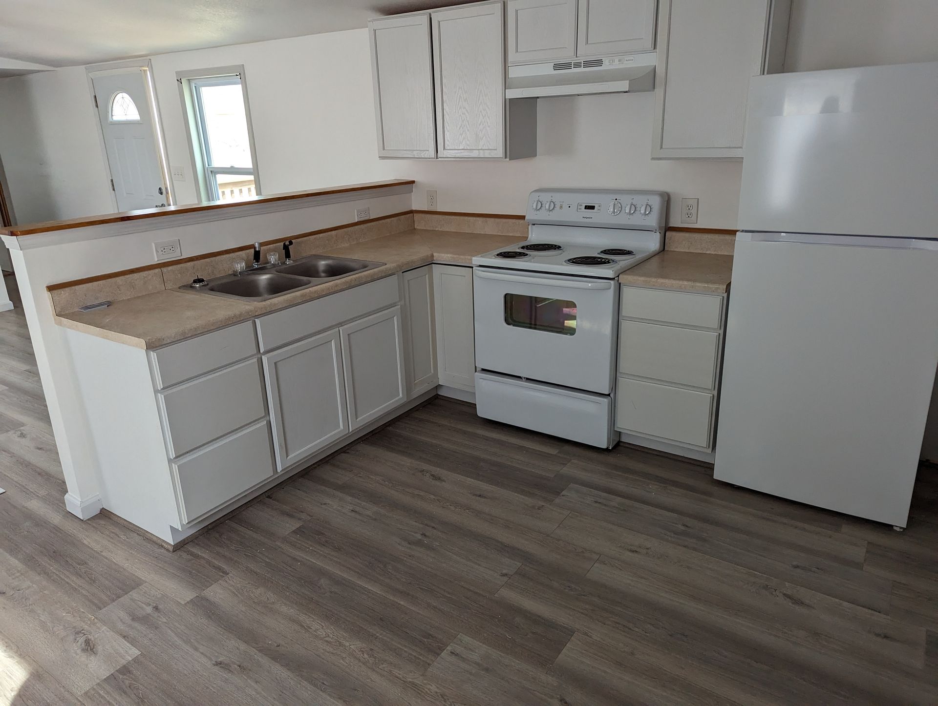 A kitchen with a stove , refrigerator , sink and cabinets.
