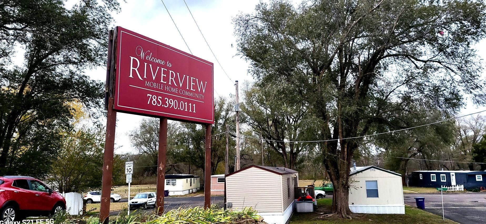 A red sign for riverview mobile home park is sitting in front of a trailer park.