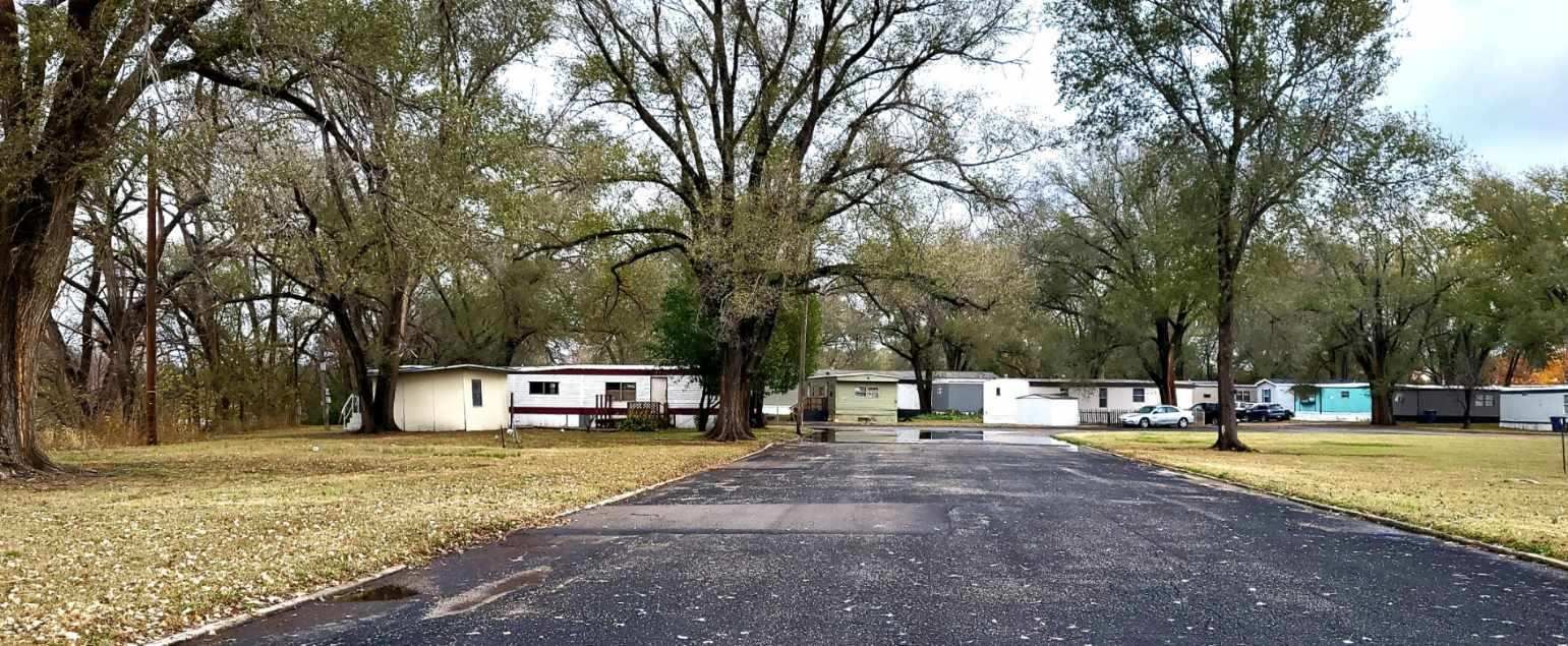 A road leading to a mobile home park surrounded by trees.