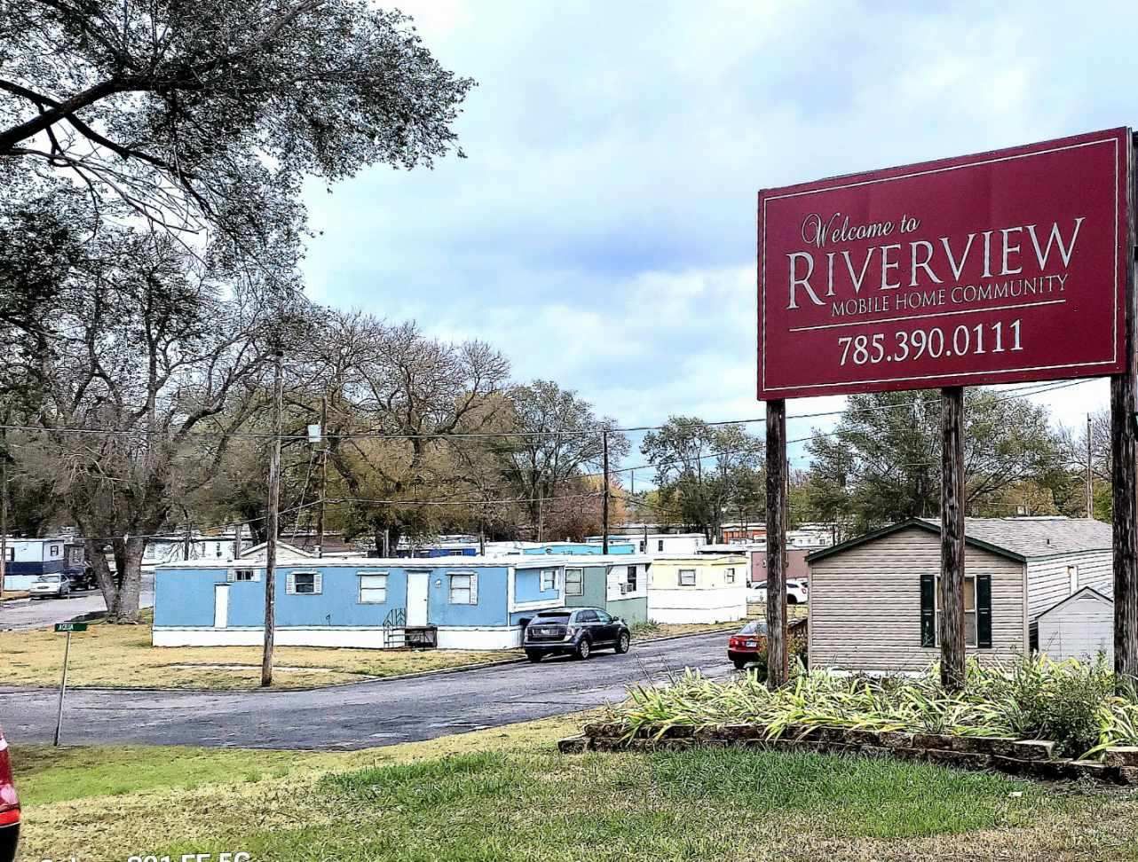 A red riverview sign is sitting in the middle of a grassy field.