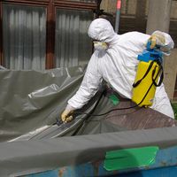 person in white suit spraying asbestos