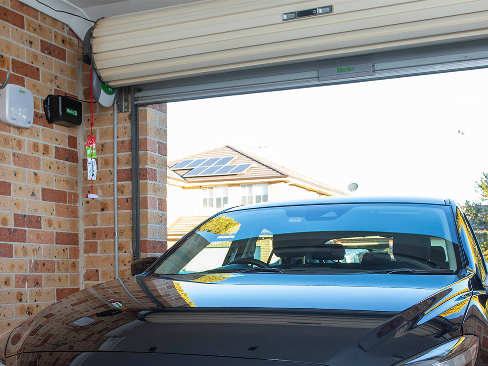 A car is parked in a garage with a garage door open.