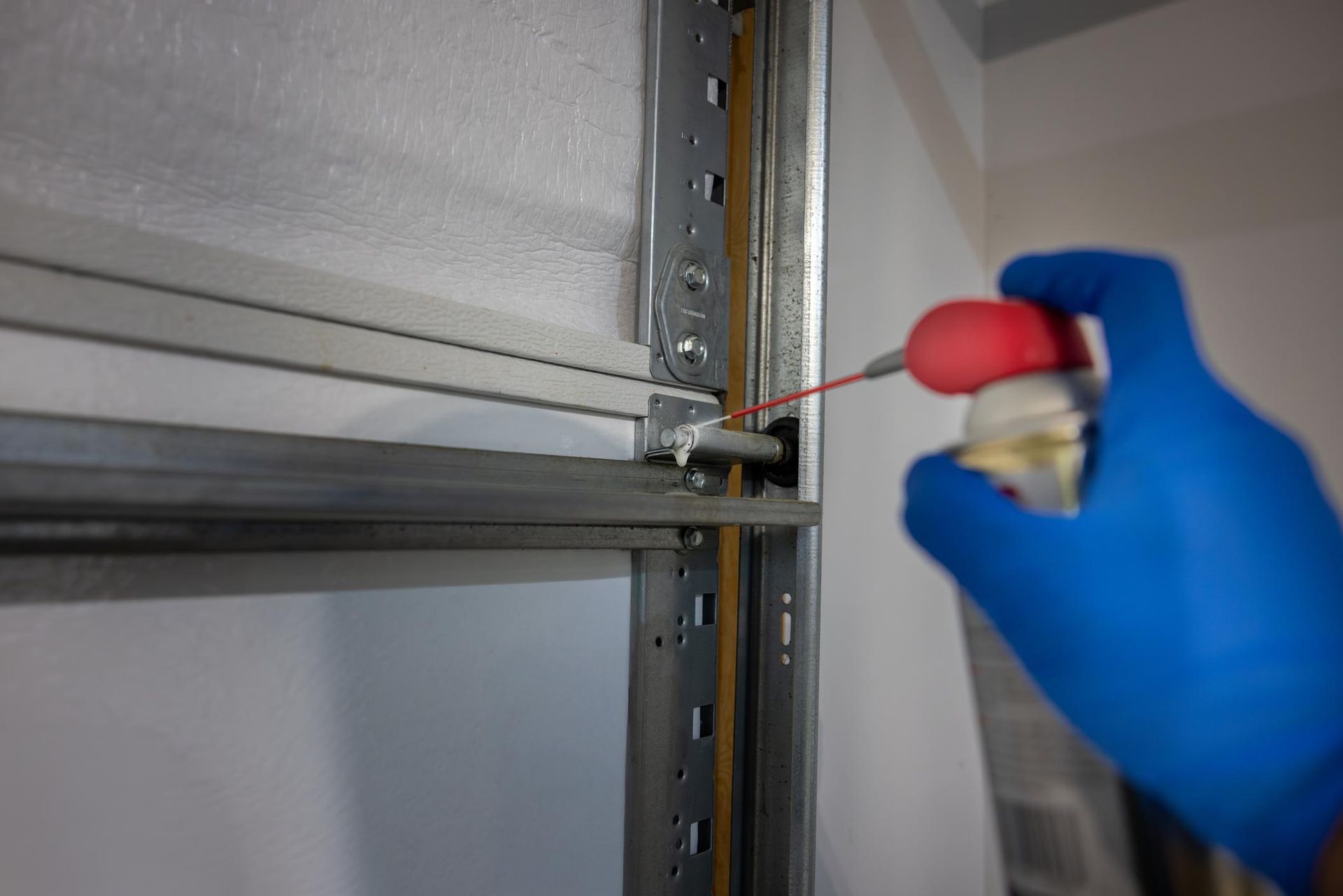 Garage door maintenance service inspecting and lubricating rollers in a residential home