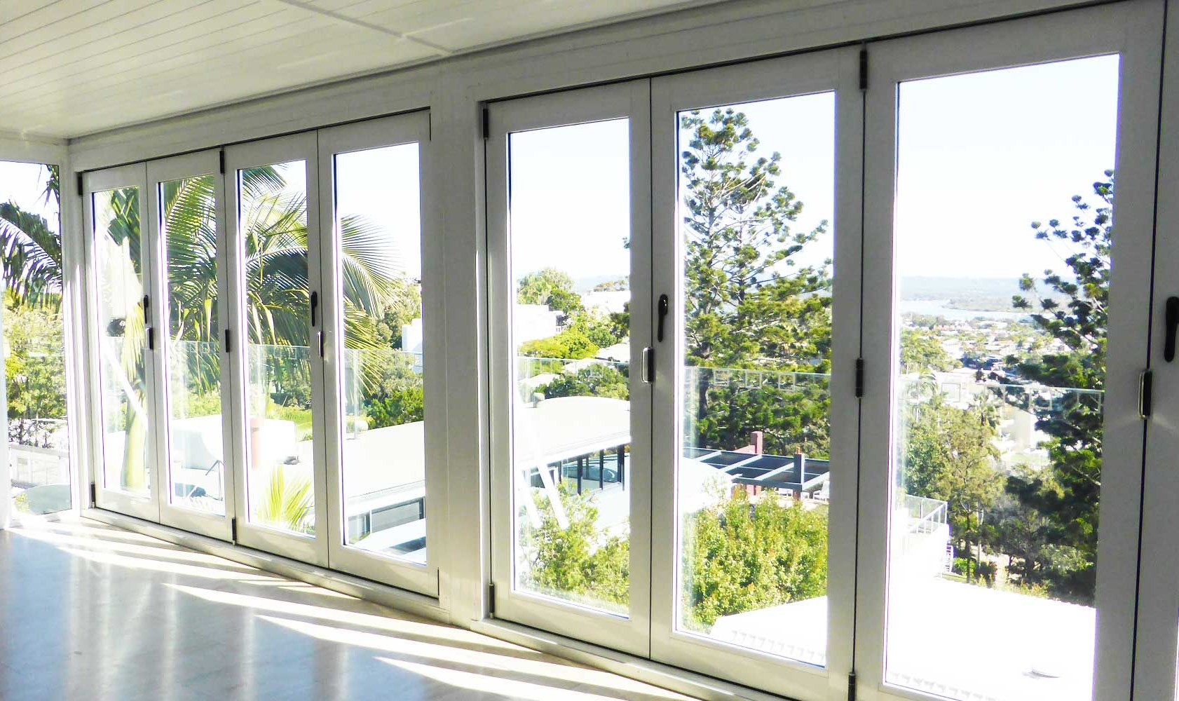 Aluminium bi-fold doors opening to a bright coastal view in Noosa home, showcasing sleek design