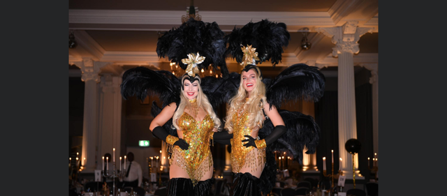 Friends of Alfie Martin £1 Million Ball. Two women dressed in black and gold costumes