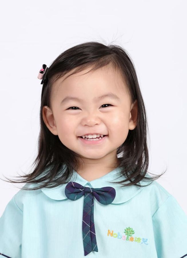 笑容燦爛的小孩，身穿藍色制服，繫著領結。