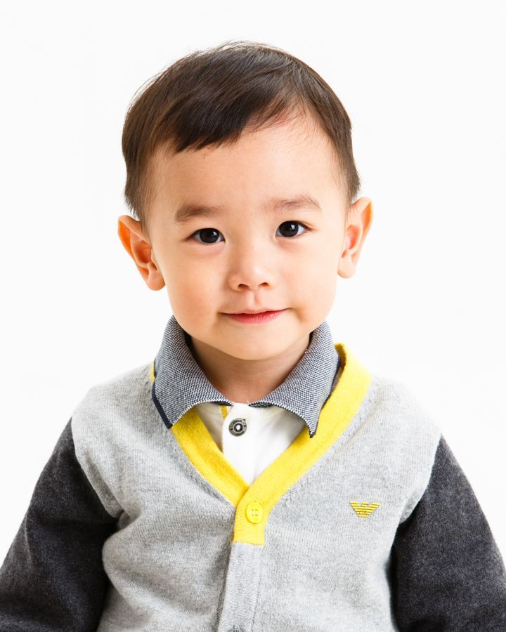 微笑的亞洲幼兒穿著黃色飾邊的灰色毛衣。