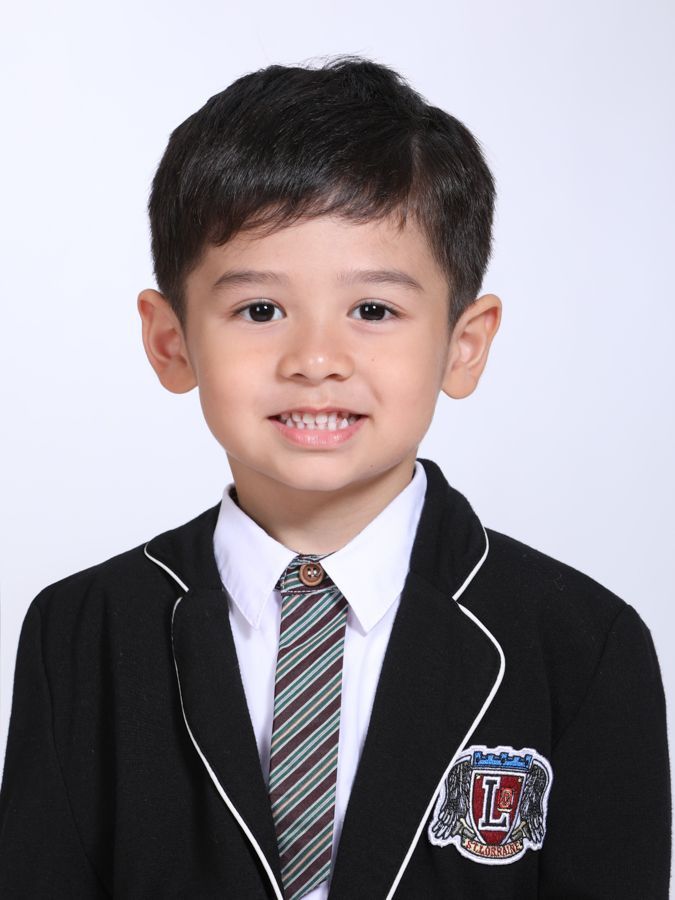 穿著校服的小男孩，在白色背景下對著鏡頭微笑。