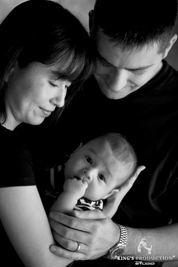 父母抱著嬰兒，都低著頭，黑白照片。