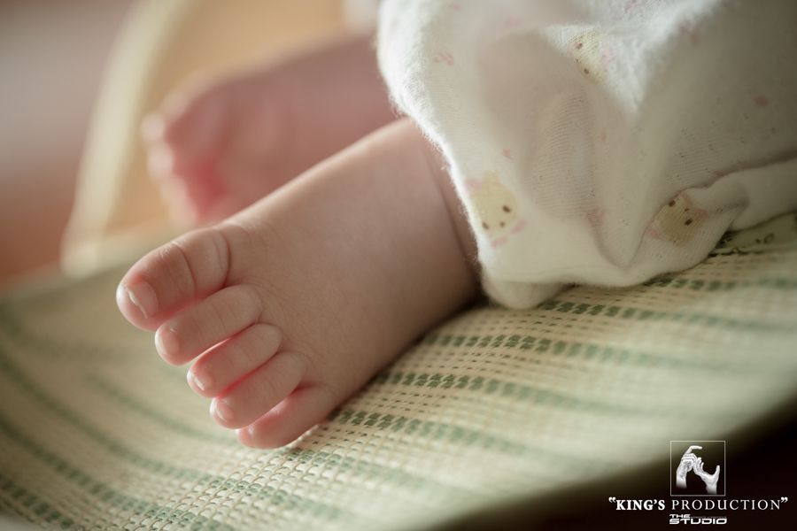 嬰兒小腳的特寫，粉紅色的腳趾，放在有條紋、有紋理的表面上。