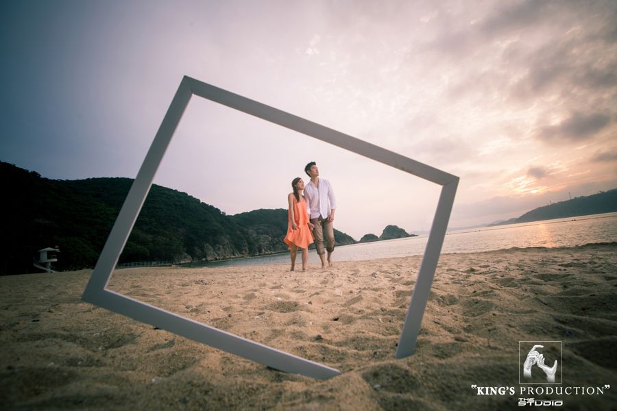 日落時分，一對情侶被海灘上傾斜的廣場包圍，背景是山脈。