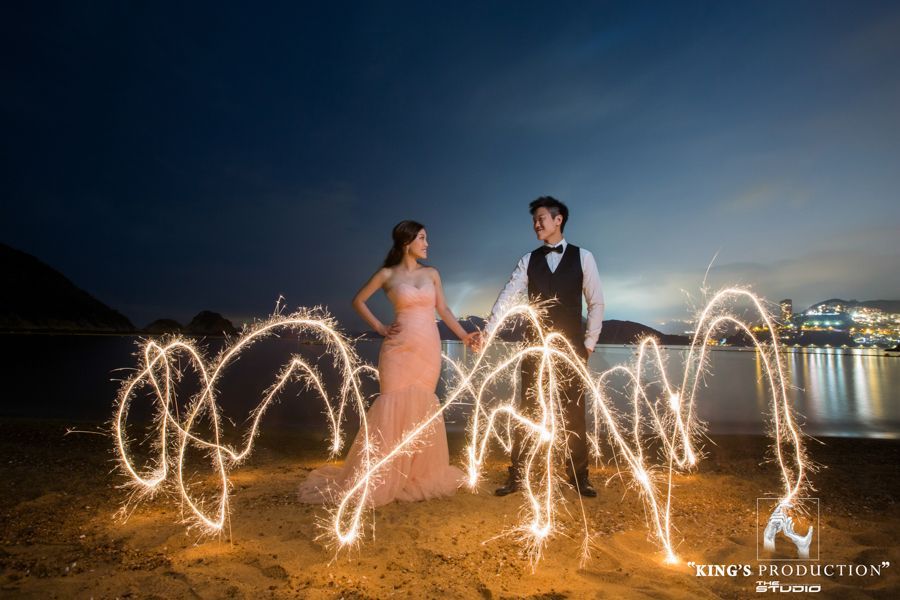 黃昏時分，一對情侶手牽手，海灘上火花四濺，燈光閃爍。