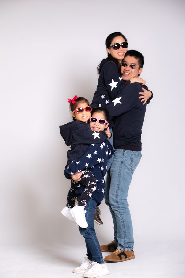 一家四口戴著太陽眼鏡，疊在一起，在白色背景下微笑。