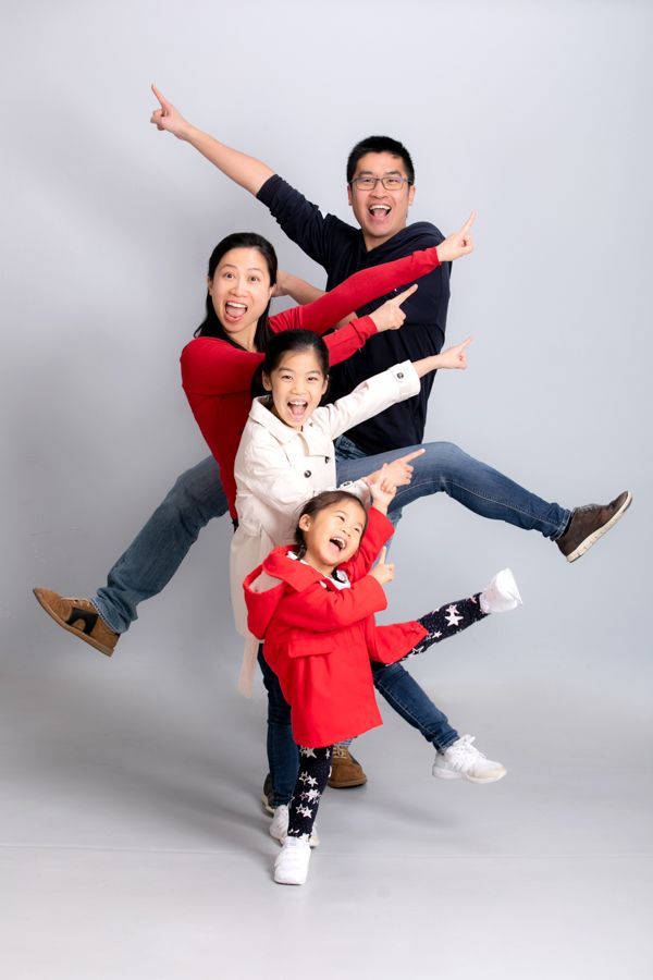 一家四口跳起來指指點點，張開雙臂微笑。