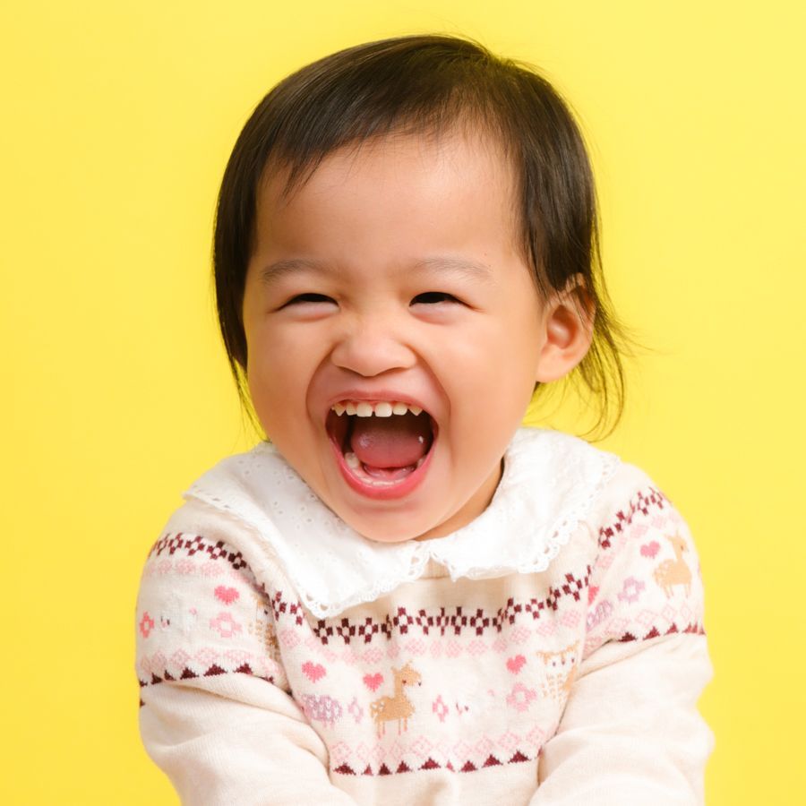 小孩張大嘴巴大笑；黃色背景。