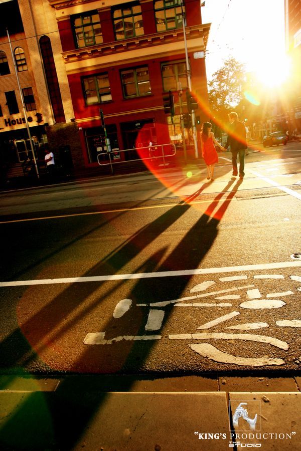 行人行走，城市街道上長長的影子。明媚的陽光。自行車道標記。紅磚建築。