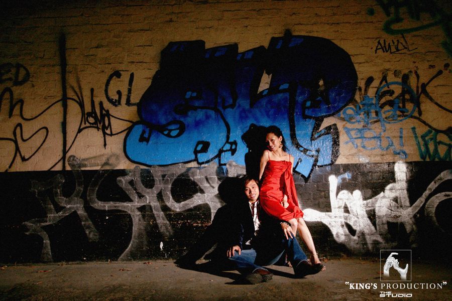 城市環境中的一對夫婦，身穿紅衣的女子坐在男子的腿上。