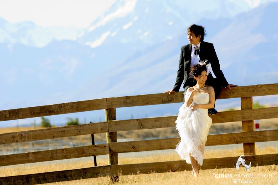 一對身著婚禮服裝的夫婦在山景木柵欄附近擺姿勢。