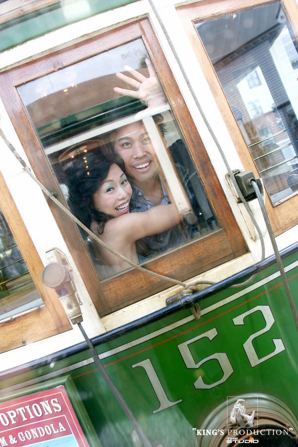 一對夫婦在一輛綠色電車的車窗外微笑著揮手。車窗外可見「152號」車牌。