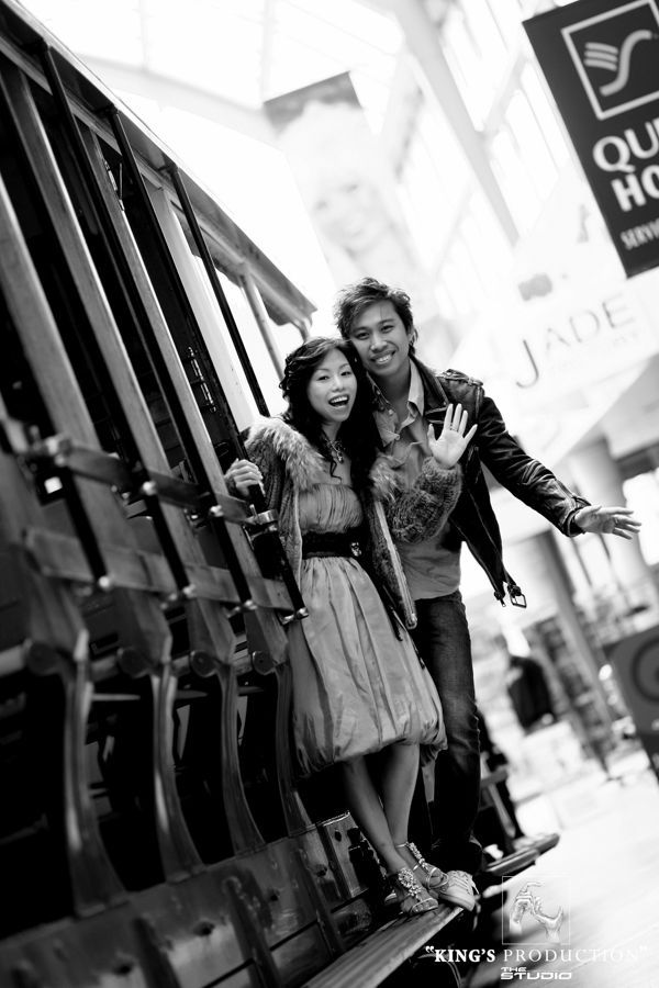 一對夫婦在纜車旁擺姿勢，微笑著張開雙臂。舊金山。黑白照片。