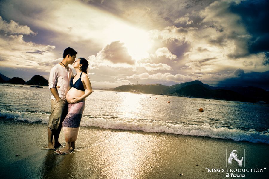 海灘上接吻的情侶；孕婦、晴朗的天空、海洋。