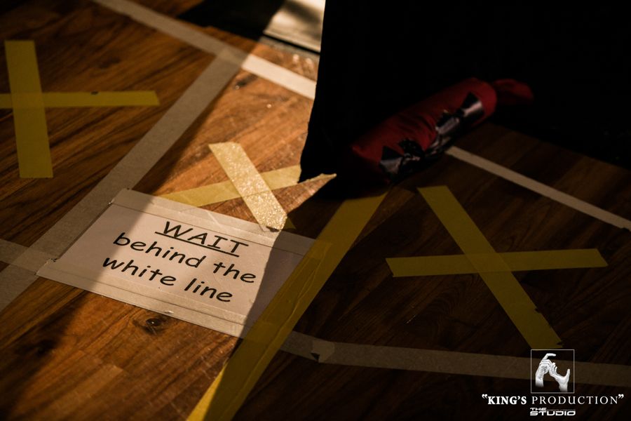 木地板上貼著膠帶，還有一塊牌子，上面寫著「在白線後面等候」；背景中有拳擊手套。