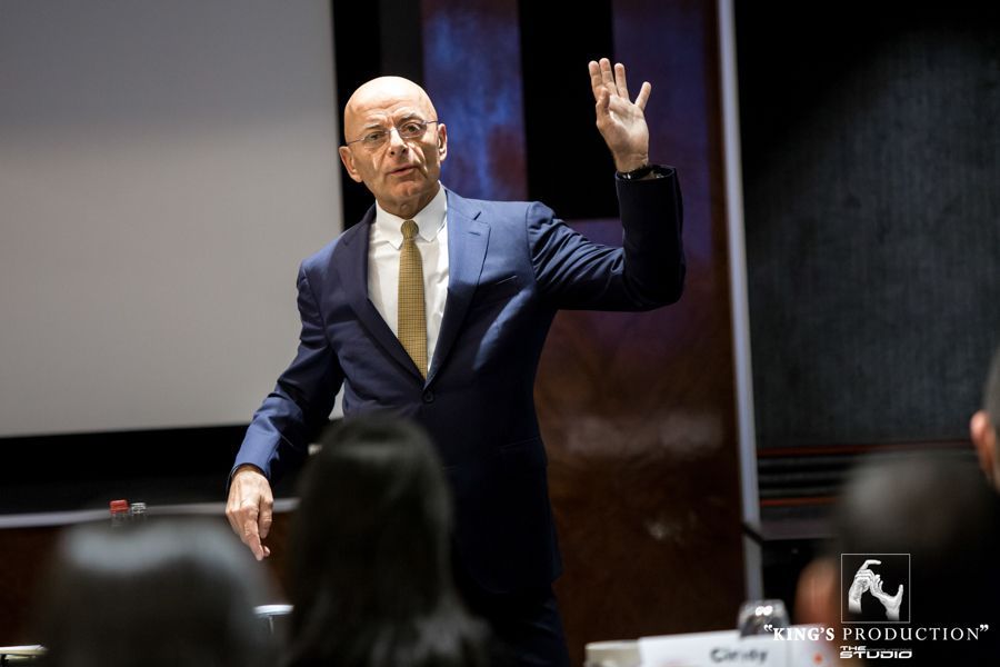 身穿西裝的男子在房間裡演講時舉起手做手勢。